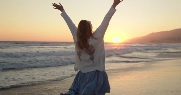 Silueta de mujer joven feliz sonriente divirtiéndose en la playa del océano al atardecer — Vídeos de Stock