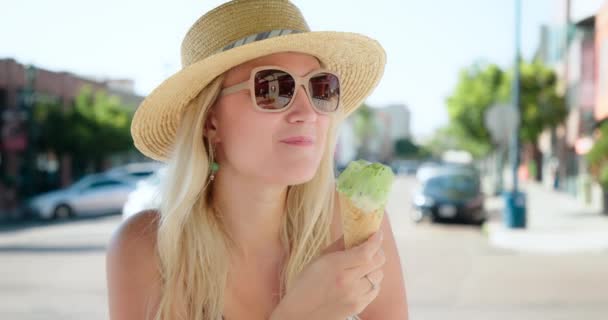 Joven rubia comiendo delicioso helado de helado italiano en un cono de gofre 4K — Vídeos de Stock