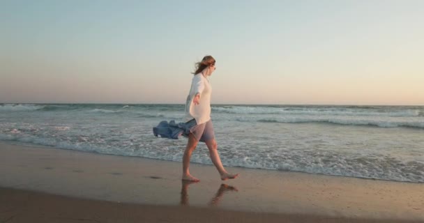 Filmagem cinematográfica em câmera lenta 4K de uma jovem mulher desfrutando do oceano e da natureza ao pôr do sol — Vídeo de Stock