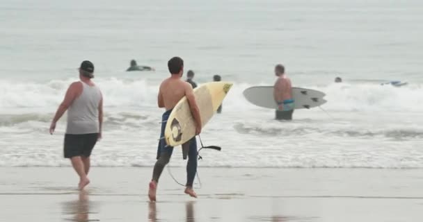 Strand van Malibu, Pacific 2020. Actieve man rent de oceaan in met surfplank — Stockvideo