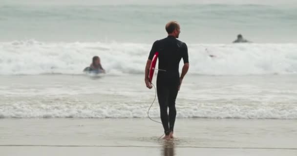 Playa de Malibú, costa del Pacífico, 2020. Slow motion 4K de hombre surfista con tabla de surf — Vídeos de Stock