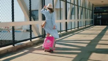 Yüz maskeli kadın yavaş hareket ediyor. Havaalanı terminalleri arasında yürüyen kadın 