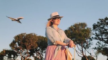 Yavaş çekim yolcusu günbatımının tadını çıkarıyor ve arka planda bir jet uçağı var.