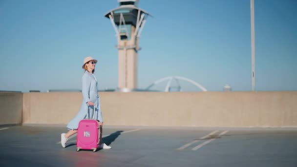 Zpomalit stylový cestovatel žena s letištní věží na pozadí — Stock video