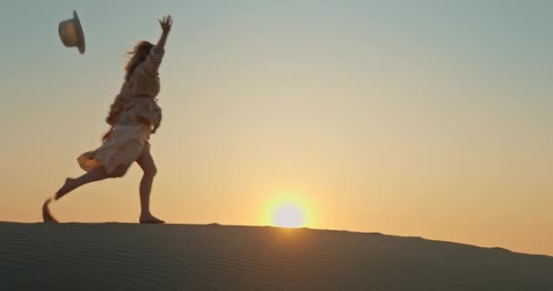 Frau läuft durch Sanddüne mit goldenem Sonnenuntergang im Hintergrund. Inspirierendes 4K — Stockvideo