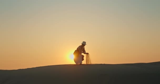 Donna felice con sabbia che soffia via dal vento con tramonto dorato su sfondo — Video Stock