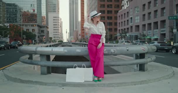 Movimiento lento de la mujer de moda con el centro de la ciudad en el fondo. Compras 4K — Vídeo de stock