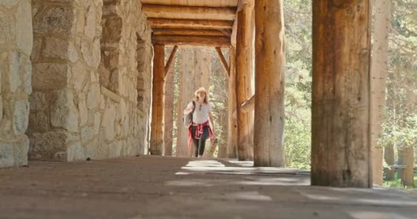 美丽的女旅行家走在森林里的石屋旁边，4K — 图库视频影像