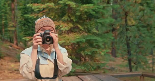 Bir kadın kamerada sonbahar ormanının fotoğrafını çekiyor. Doğadaki güzel gezgin — Stok video