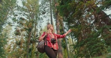 Yeşil ormanda ağır çekimde yürüyen kadın. Düşük açılı gülümseyen kadın, 4K