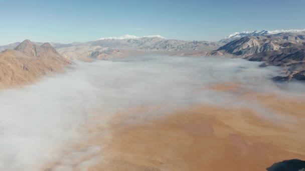古代の湖のベッドは、雪の山の峰に囲まれた霧の雲に覆われている — ストック動画