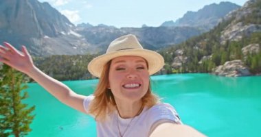 Güzel bir kadın açık havada akıllı telefon kullanarak görüntülü konuşma yapıyor. Macera paylaşımı 4K