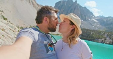 Gezgin çift, güzel mavi göl, 4K 'daki dağın zirvesinde selfie çekiyorlar.