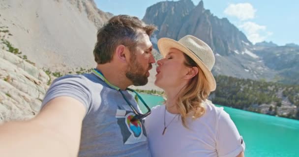 一对旅行的夫妇在美丽的蓝色湖畔的山顶上自拍 — 图库视频影像