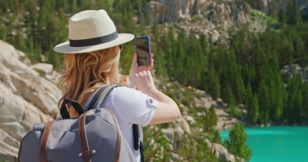 Podróżniczka robi zdjęcia na smartfonie z zielonym jeziorem. Przygoda — Wideo stockowe