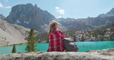 Kadın sinematik doğa manzarasını seviyor. Blue Lake 4K 'de oturan arka manzara yolcusu.
