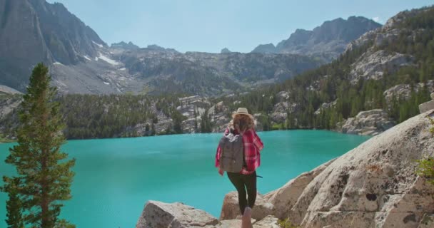 Mulher feliz correndo para o lago azul com paisagem de montanha no fundo — Vídeo de Stock