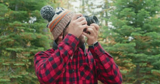 Ενηλίκων γενειοφόρος άντρας με καπέλο με κάμερα που τραβάει φωτογραφίες από την πρώιμη φθινοπωρινή φύση 4K — Αρχείο Βίντεο