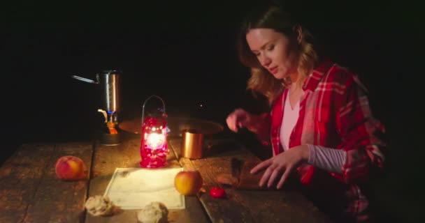Kobieta kroi chleb na kempingu z jasnopomarańczowym ogniskiem na tle — Wideo stockowe