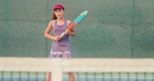 Спортивная девушка играет в теннис на корте. Активный подросток бьет по мячу за ракеткой — стоковое видео