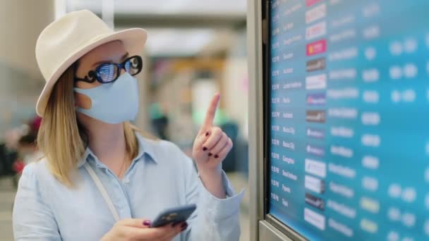 Viajero femenino en COVID-19 mascarilla comprobar el horario de vuelo en el aeropuerto 4K — Vídeos de Stock