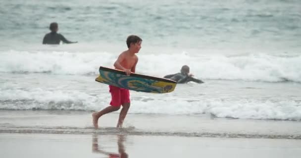 Malibu strand 2020. Barn som har kul på havsstranden. Pojkar med boogie board — Stockvideo