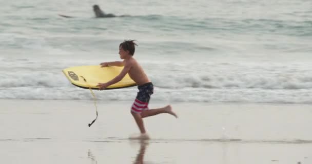 Malibu strand 2020. Tiener jongen speelt met boogie board — Stockvideo