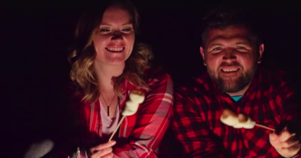 Cinemática vista romántica pareja burlándose de tostadas malvavisco en hoguera — Vídeo de stock