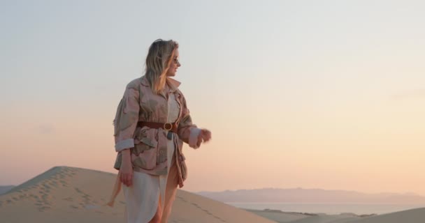 아름다운 미소짓는 여인이 석양 때의 황금 시간에 모래 언덕을 걷고 있다 — 비디오
