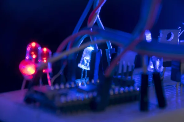 面包板 Arduino 纳米原型板晶体管电阻在黑色皮肤上的黑暗中发光红色和蓝色 — 图库照片