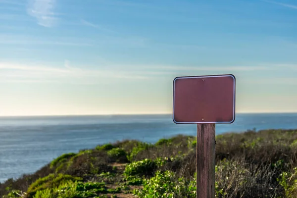 Close up image of an empty sign for your text with ocean on the background on a sunny day; State park, California, USA