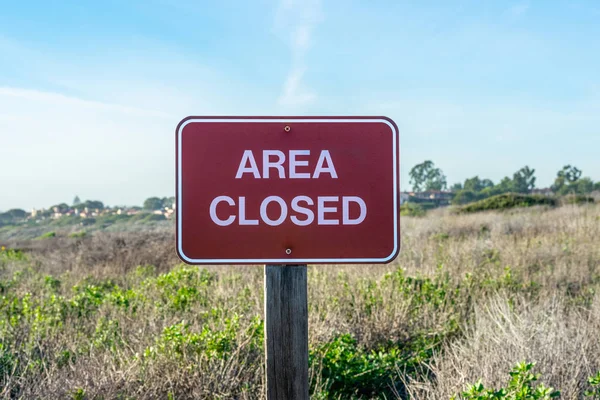 Close up image of an Area Closed sign with dry grass on the background on a sunny day; State park, California, USA; image taken during 2019 government shutdown
