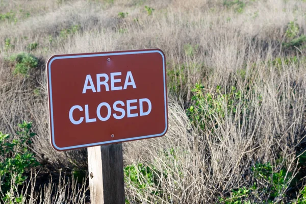 Close up image of an Area Closed sign with dry grass on the background on a sunny day; State park, California, USA; image taken during 2019 government shutdown