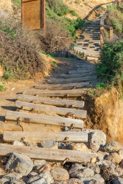 Kayaların üzerinde biten beach, önde gelen ahşap günlüklerinden yapılan eski yıpranmış merdiven durumda
