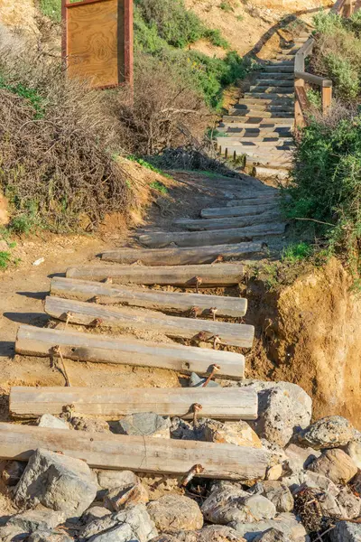 Kayaların üzerinde biten beach, önde gelen ahşap günlüklerinden yapılan eski yıpranmış merdiven durumda