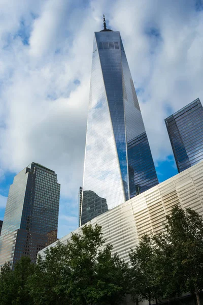 Bir Dünya Ticaret Merkezi ve çevredeki binalara, görünümü üst yüzey yansıtan mavi gökyüzü ve bulutlar cam