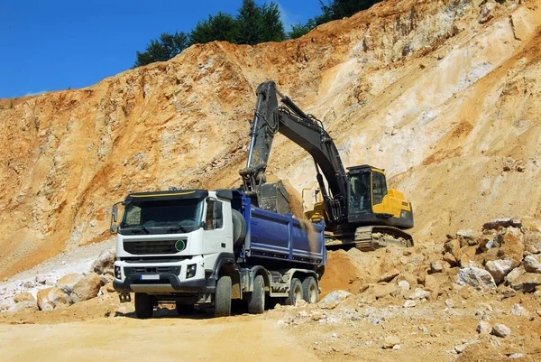Yellow excavator loading stones in a truck