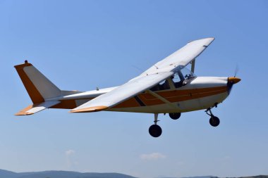 Mavi gökyüzünde uçan küçük bir motorlu uçak.