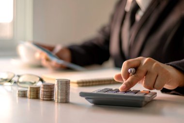 İş kadını ofis giderlerini, finans fikirlerini ve kredi yatırımlarını hesaplamak için hesap makinesine basıyor.