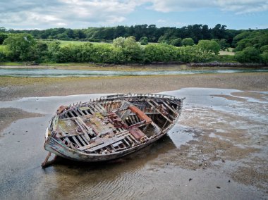 Düşük tide, kendi tarafında eski bir ahşap balıkçı teknesi yatıyordu.