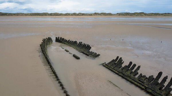 Ruins of an old wooden ship jutting out after low tide