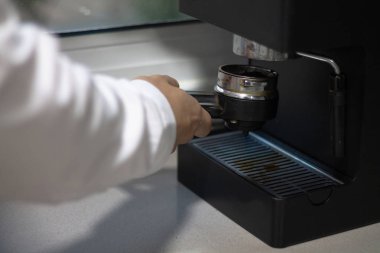 Bir tabloda bir kahve makinesi kahve kolu tutan adam