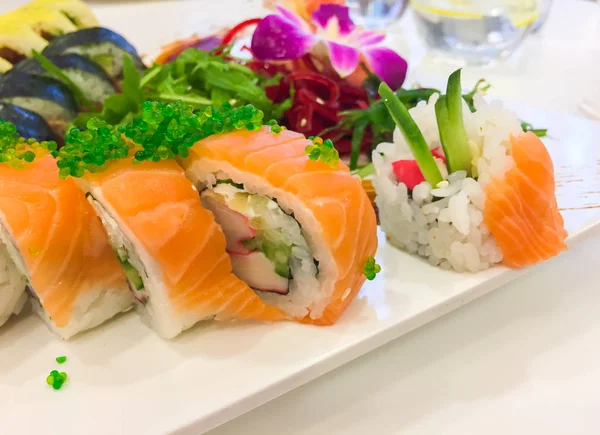 Variedade de rolos de sushi em uma placa branca — Fotografia de Stock