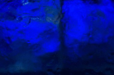 Küçük kabarcıklar mavi ışıkla aydınlatılmış açık şeffaf buzlu. Buzun yapısını fantastik desenler oluşturur.