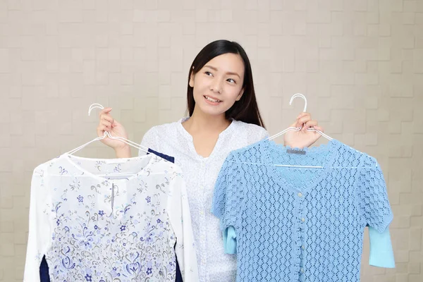 一个年轻女子手持衣服和微笑的肖像 — 图库照片