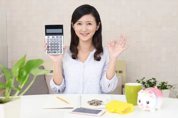 Smiling Asian woman with money and calculator