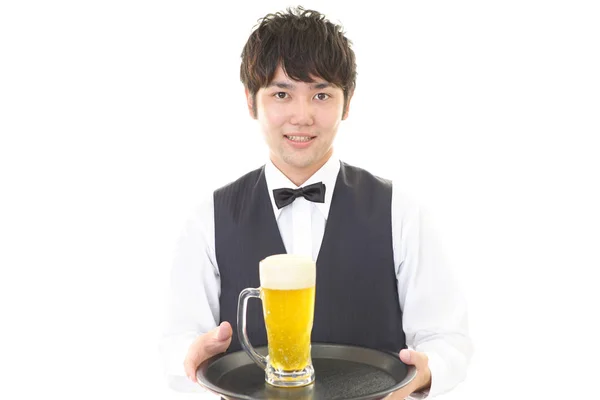 Smiling Asian waiter with a mug of beer