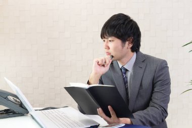 Asya işadamı bilgisayar kullanarak onun ofisinde çalışan.