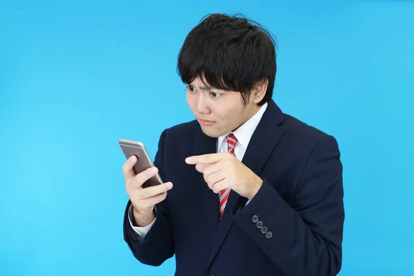 Disappointed Asian businessman with a smart phone