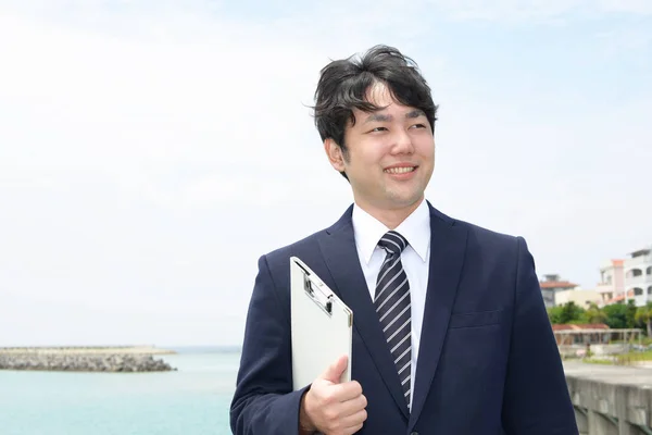 Smiling Asian businessman by the sea